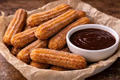 Хрустящие испанские чуррос с сахарно-коричной посыпкой и насыщенным шоколадным соусом.