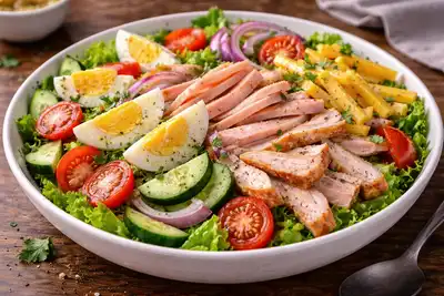 Сытный салат с индейкой, ветчиной, яйцом, сыром и хрустящими овощами в классическом американском стиле.